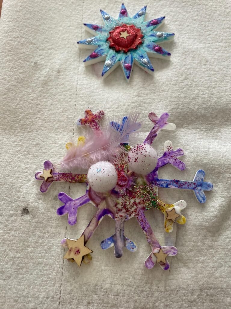 Two kids craft snowflakes, colored and painted.