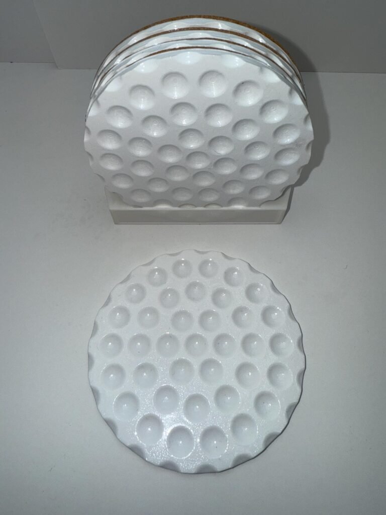 Golf ball drink coaster set with ridge indentations.